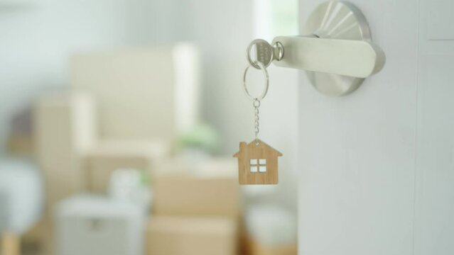 Moving house, relocation. The key was inserted into the door of the new house, inside the room was a cardboard box containing personal belongings and furniture. move in the apartment or condominium