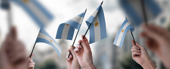 A group of people holding small flags of the Argentina in their hands