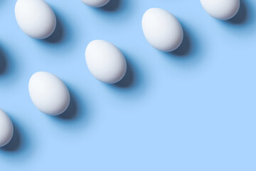 Creative composition with pattern from white eggs on blue background. Copy space