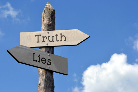 Naklejki Truth and lies - wooden signpost with two arrows, sky with clouds