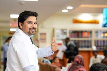 Indian male doctor showing thumps up at hospital.