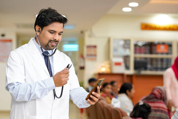 Indian male doctor using smartphone at hospital.