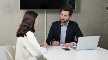 Successful businessman interviewing a smart young woman for a job in a modern office. Professional respectful atmosphere with engaging busy conversation. Both parties leave positive and hopeful.
