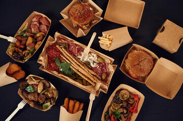 Top view of table with food on it. Meat, vegetables, French fries, burger, mushrooms