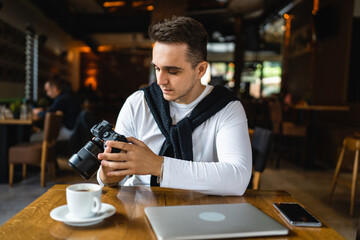 one man use digital mirrorless camera while sit at cafe or restaurant