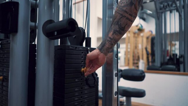 Young and handsome tattooed man training hard in gym. Lifting weights.