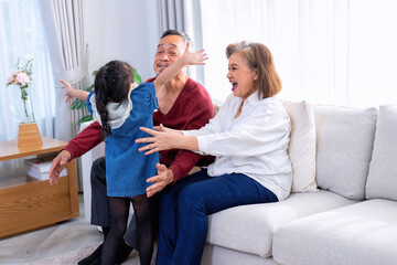 Obraz premium Grandfather smiling embracing her granddaughter happy granny enjoying hug her grandchild at home