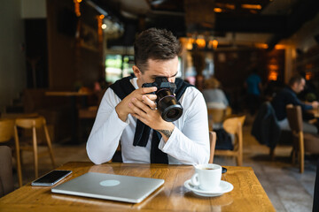 one man use digital mirrorless camera while sit at cafe or restaurant