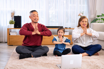 Fototapeta premium The family have fun relax engaged in fitness yoga at home using online instruction from laptop