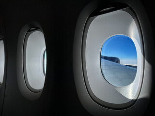 Row of windows inside a passenger jet cruising at altitude. No people.