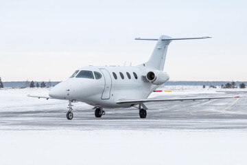 White business jet taxiing on airport taxiway in winter