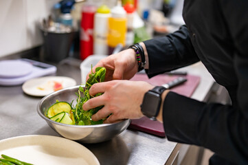 Chef hand mixing a vegetable salad in stainless steel bowl on kitchen