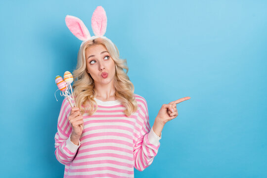 Photo of funky dreamy lady dressed pink pullover rabbit headband rising eggs empty space isolated blue color background
