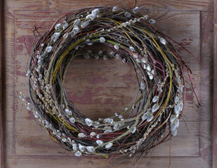 Easter wreath on a wooden door made of branches, decorated with a flowering willow. Decoration on the door for Easter