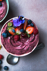 Two summer acai smoothie bowls with strawberries, blueberries,   on gray concrete background....