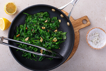 Sauteed spinach with garlic in a skillet - obrazy, fototapety, plakaty