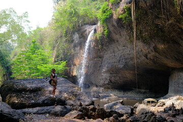 A young woman visiting Haew Suwat Waterfall, a natural beauty in a large forest