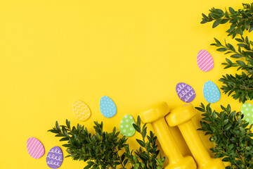 Two heavy dumbbells, boxwood branches and decorative Easter eggs. Healthy fitness lifestyle...
