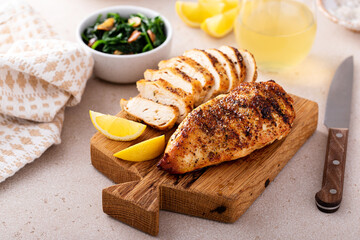 Grilled chicken with spice rub and lemon on a cutting board - obrazy, fototapety, plakaty