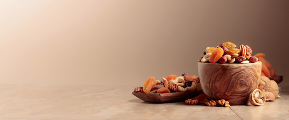 Dried fruits and nuts on a beige ceramic table.