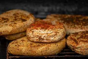 Smoking bio natural seasoned cheese with spices in a smoker in a street food market, close up