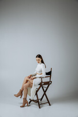 A girl in white clothes on a gray background of a photo studio