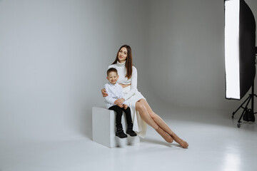 A little boy with his mother on a gray background of a photo studio