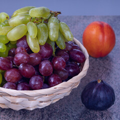 berries of white and red grapes and fresh fruits in a straw basket on a dark wooden background - 580766835