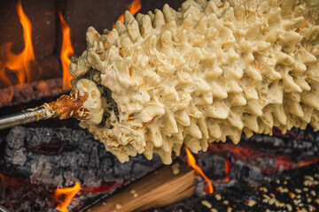 Preparing Lithuanian tree cake, šakotis or baumkuchenas, Polish sękacz, Belarusian bankucha, German baumkuchen made of butter, egg whites and yolks, flour, sugar, and cream, cooked over an open fire