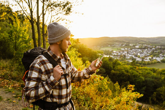 Young man tourist using mobile phone while standing at forest glade