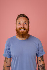 Adult redhead bearded tattooed smiling man in t-shirt looking upwards