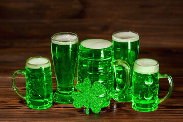 concept of St Patricks day with glasses of green beer, shamrock on vintage wooden background, close up