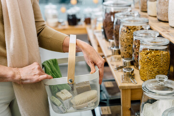 Close up shot of woman carrying shopping basket and shopping groceries zero waste shop with glass...