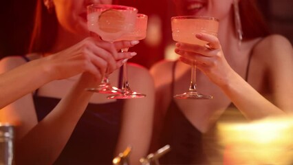 Close-up of cocktail glasses clinking. Beuatiful young girls meeting at bar, restaurant, talking and drinking coctails. Friendship, meeting, fun, clubbing, party and celebration concept