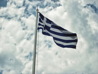 Greek flag waving against a blue cloudy sky background