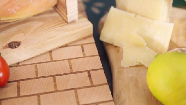 Cured prosciutto slices falling down on wooden board, dry cured parma ham antipasto served with fresh tomatoes, red wine and parmigiano cheeses, Italian jamon cut slices