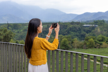 Female hiker capturing mountain view on phone