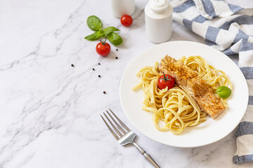 Gluten-free spaghetti pasta with grilled salmon in cream cheese on a marble background. Copy space.