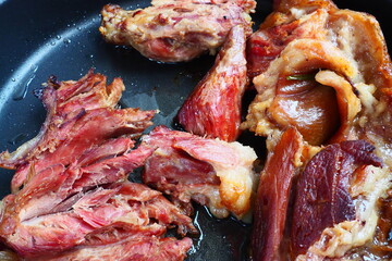 Roasted smoked pork shoulder or knee. Delicious meat on a black baking sheet with drops of...