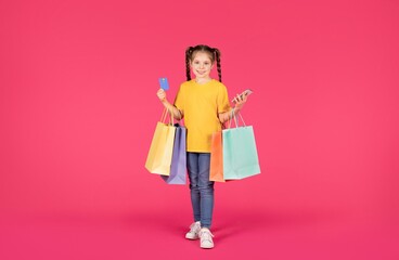 Little Shopaholic. Cute Preteen Girl Holding Smartphone, Credit Card And Shopping Bags