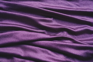 Fototapeta na wymiar Velour fabric, similar to silk. Textiles in a folds and beautiful waves. Purple, pink, magenta shades on the drapery. Sewing material for evening dresses, furniture upholstery, curtains and interior.
