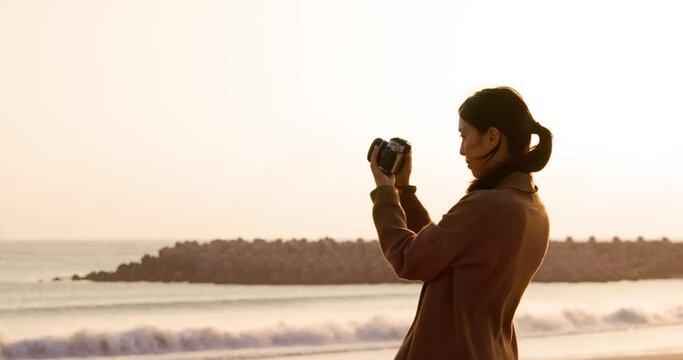 Woman use digital camera to take photo at the beach