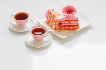two cups of tea with pink cake on white table