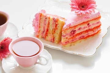 two cups of tea with pink cake on white table
