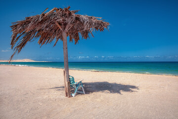 Sommerstrandszene mit Stuhl und sanftem blauen Meer,blauer Himmel, Menschenleer, Urlaub und Erholung