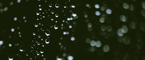 Atmospheric minimal monochrome backdrop with rain droplets on glass. Wet window with rainy drops and dirt spots closeup. Blurry minimalist background of dirty window glass with raindrops close up.