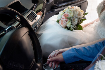 hands of the bride and groom in the car at the wedding