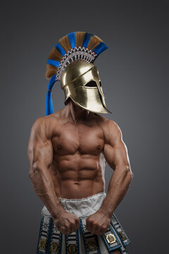 Studio shot of muscular military man from ancient greece against gray background.
