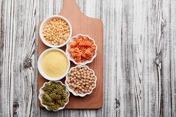 Concept of FODMAP, paleo, keto, diet, long carbohydrates, copy space. Assortment of gluten free food pasta and cereals on wooden cutting board.