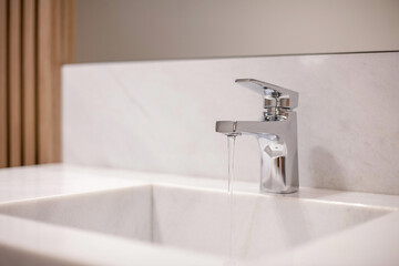 Open bathroom faucet with running water.
